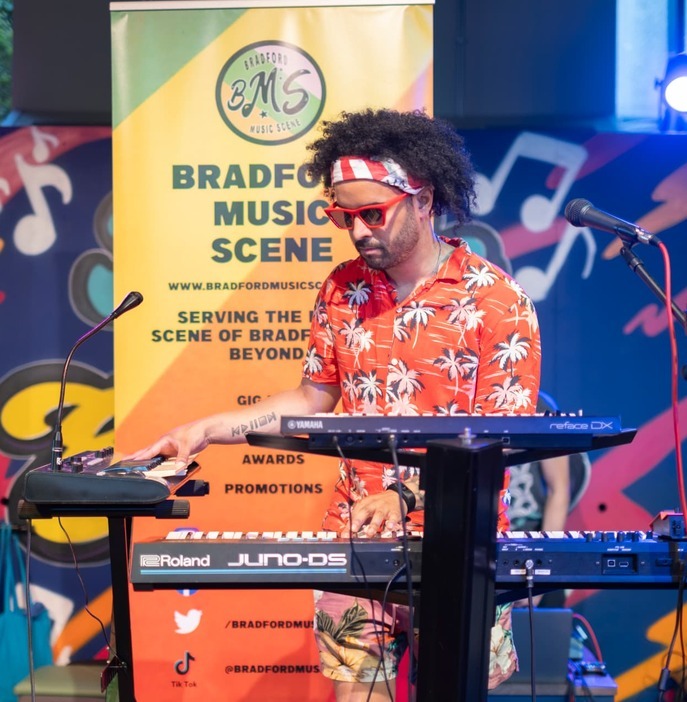 Artist performing with keyboards in front of BMS branding